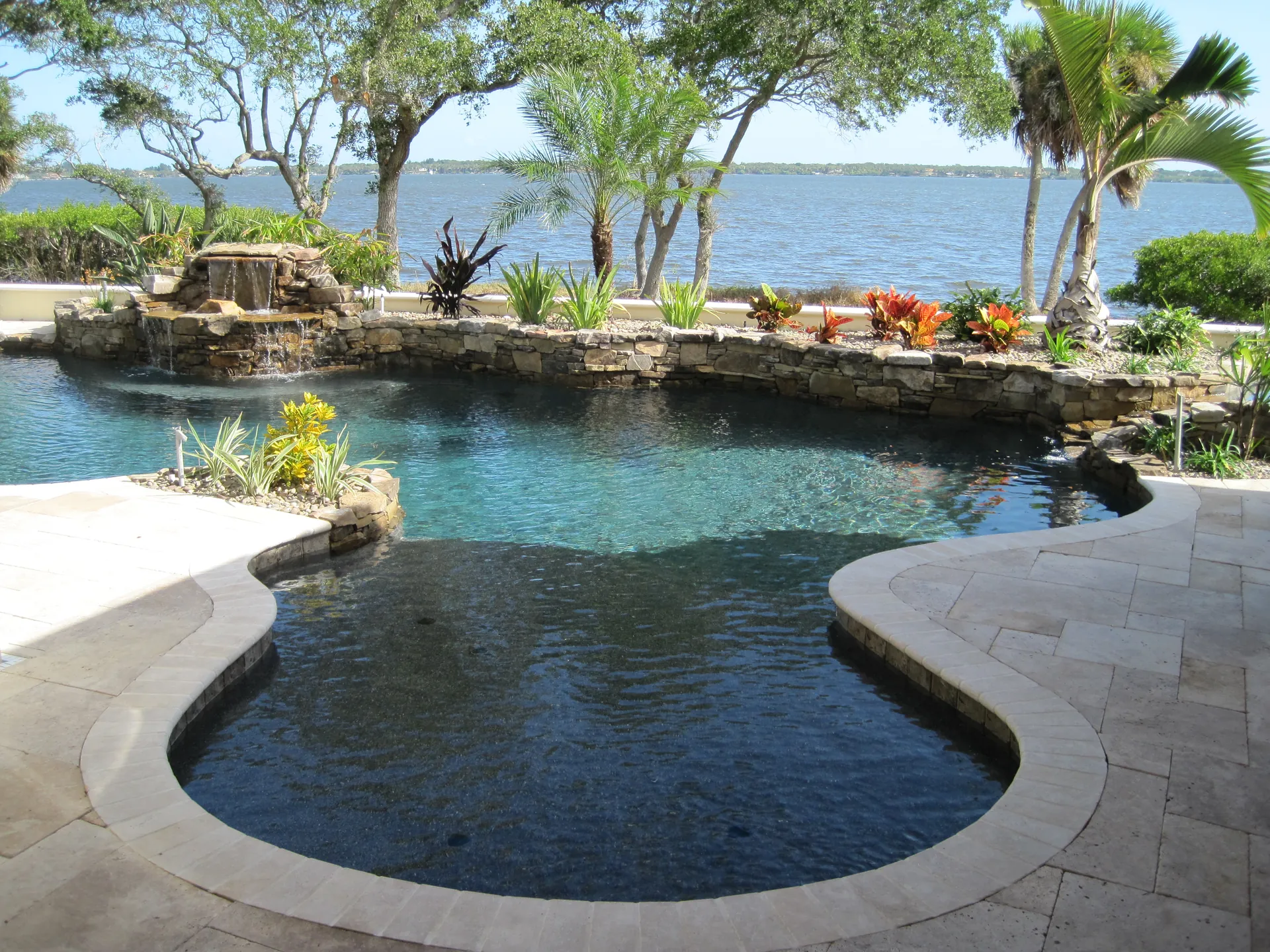 Home 2 Freeform dark bottom pool with a rock waterfall overlooking the river