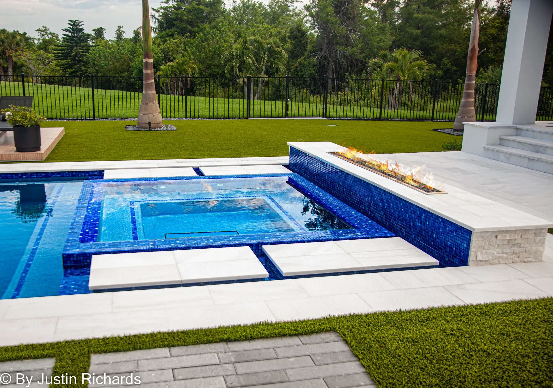 Home 3 Royal blue glass tile spa with a lit linear fire feature after a remodel