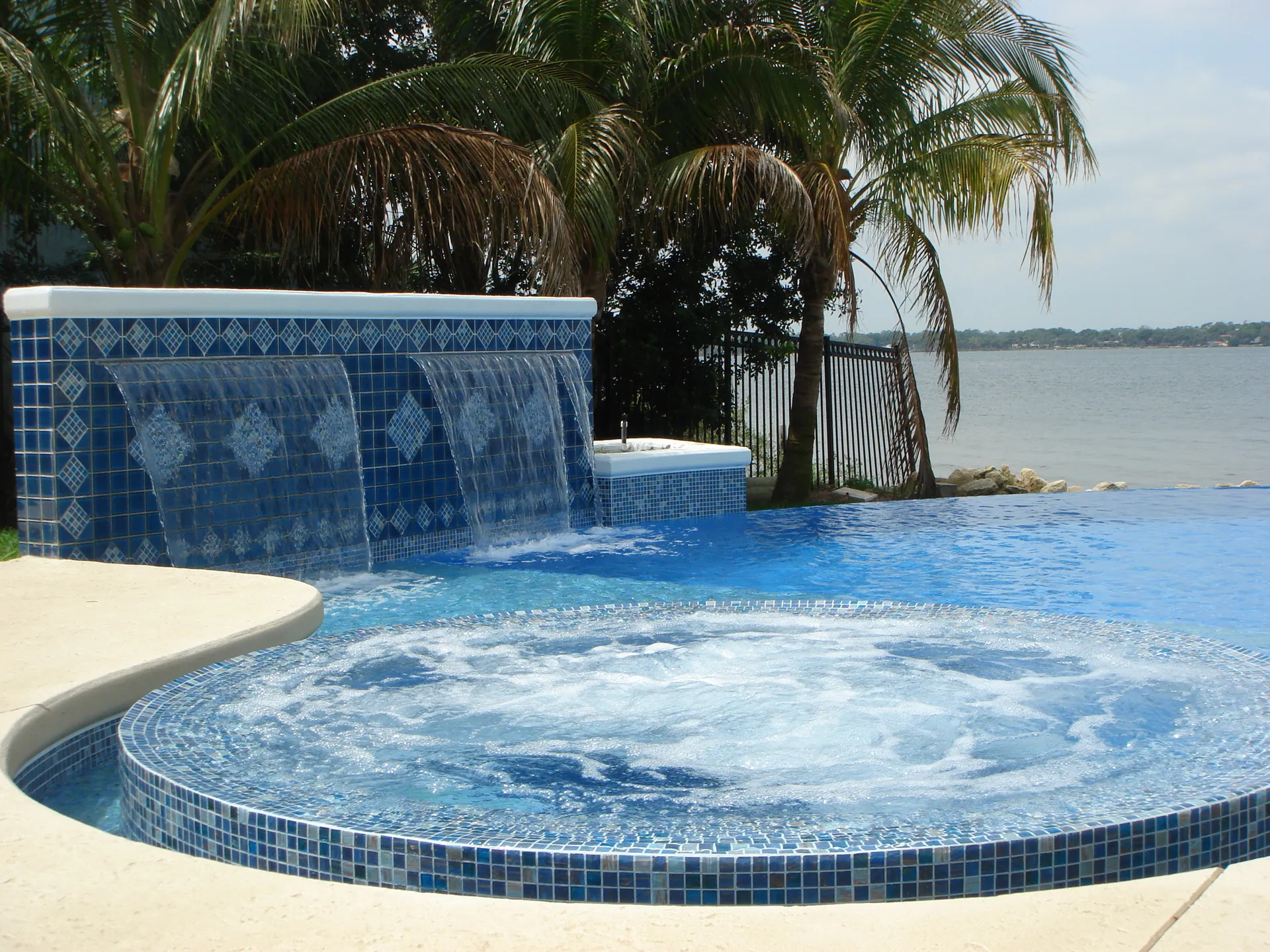 Home 7 Blue mosaic wall pouring three sheer descent waterfalls into an infinity pool